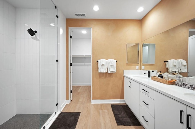 bathroom with hardwood / wood-style flooring, vanity, and a tile shower