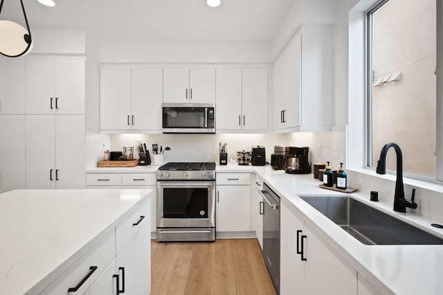 kitchen featuring white cabinetry, appliances with stainless steel finishes, sink, and light hardwood / wood-style flooring