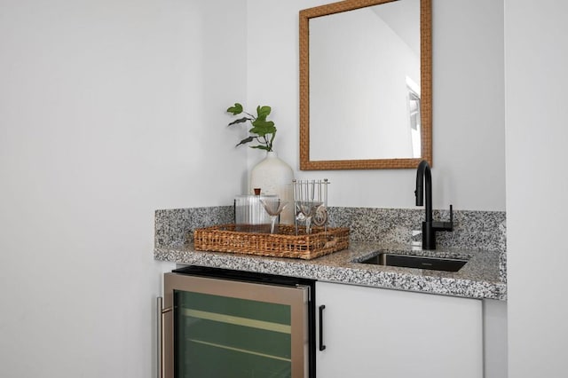 bar with wine cooler, sink, and light stone counters