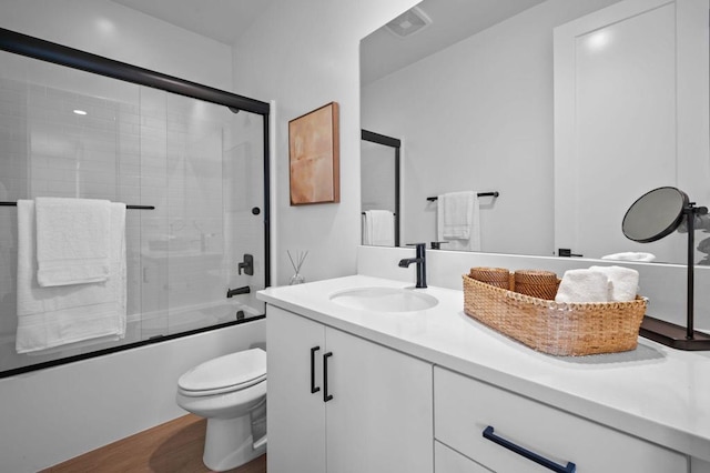 full bathroom featuring bath / shower combo with glass door, vanity, and toilet