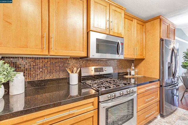 kitchen with decorative backsplash, stainless steel appliances, and dark stone counters