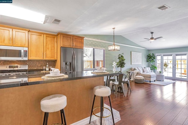 kitchen featuring dark wood-type flooring, stainless steel appliances, a kitchen breakfast bar, and french doors