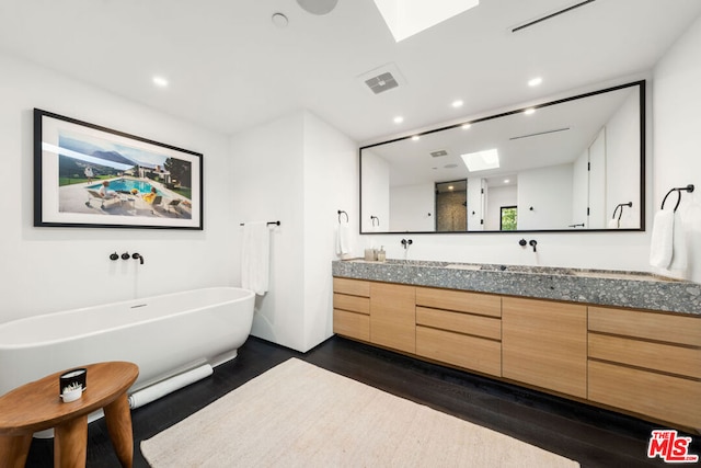 bathroom featuring vanity, a skylight, a bathtub, and wood-type flooring