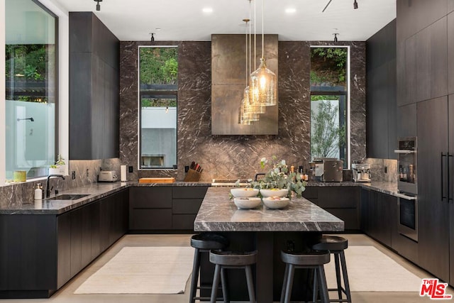 kitchen featuring pendant lighting, sink, a breakfast bar, dark stone countertops, and a kitchen island