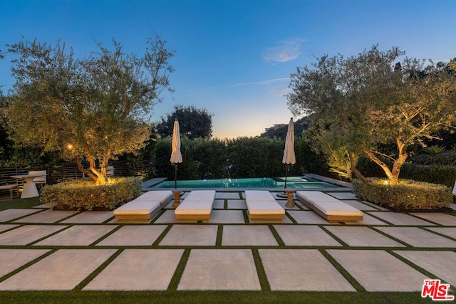 pool at dusk featuring a patio