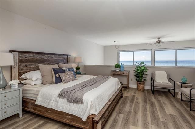 bedroom with a water view, hardwood / wood-style floors, and ceiling fan