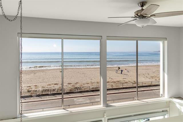 doorway to outside with a view of the beach, a water view, and a healthy amount of sunlight