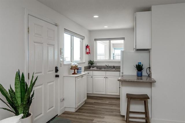 kitchen featuring a breakfast bar area, sink, light hardwood / wood-style flooring, and white cabinets