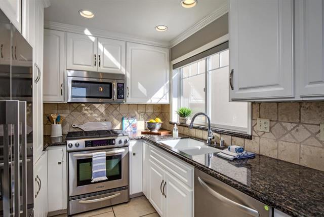 kitchen with sink, stainless steel appliances, tasteful backsplash, white cabinets, and dark stone counters