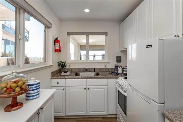 kitchen with sink, a wealth of natural light, white cabinets, and white appliances