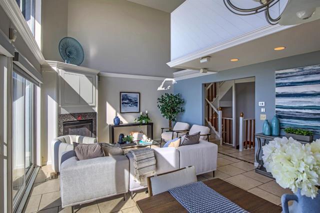 tiled living room featuring a high end fireplace and a high ceiling