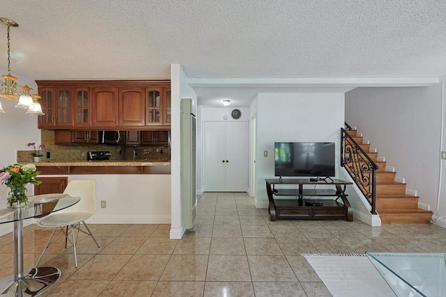 kitchen featuring a chandelier, a textured ceiling, hanging light fixtures, light tile patterned floors, and backsplash