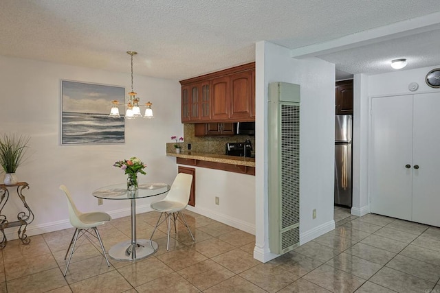 kitchen with tasteful backsplash, decorative light fixtures, a textured ceiling, light tile patterned floors, and stainless steel refrigerator