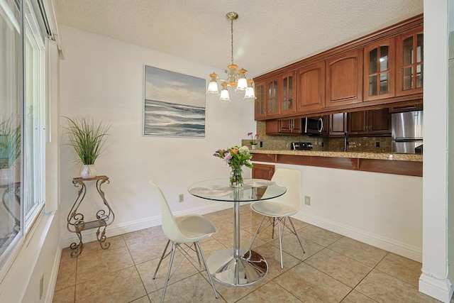 tiled dining room with a notable chandelier and a textured ceiling