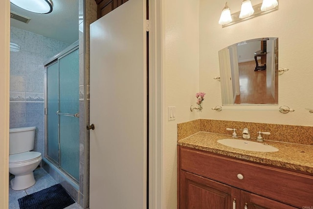 bathroom featuring walk in shower, vanity, toilet, and tile patterned flooring