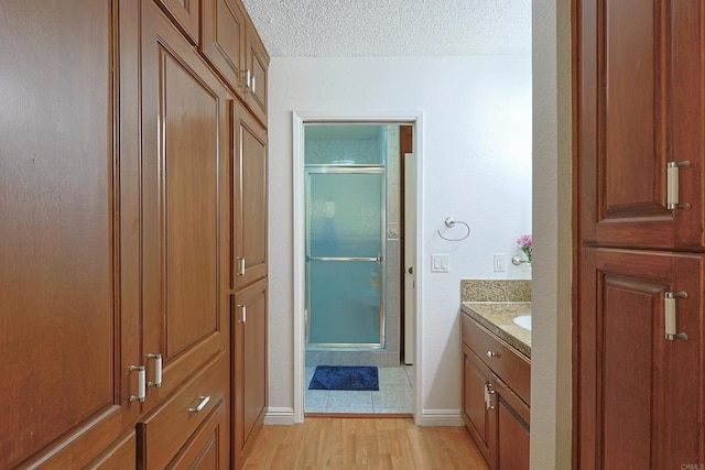 bathroom with a shower with door, vanity, hardwood / wood-style flooring, and a textured ceiling