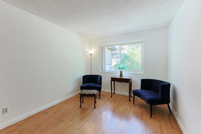 living area with a textured ceiling and light hardwood / wood-style floors