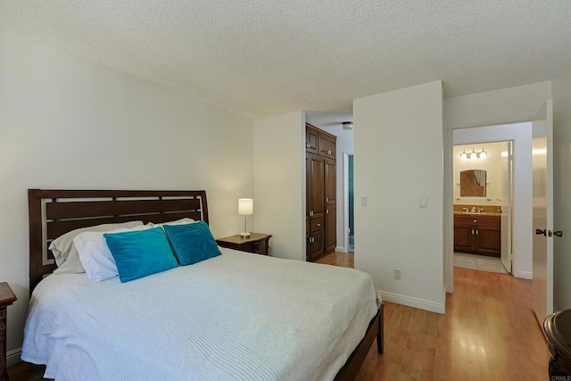 bedroom featuring sink, a textured ceiling, and light hardwood / wood-style flooring