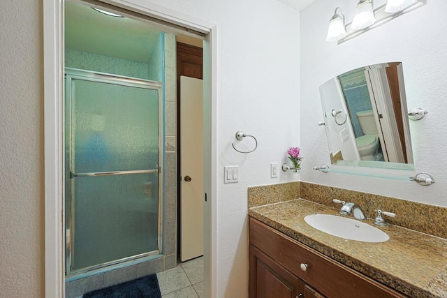 bathroom featuring vanity, tile patterned floors, toilet, and walk in shower