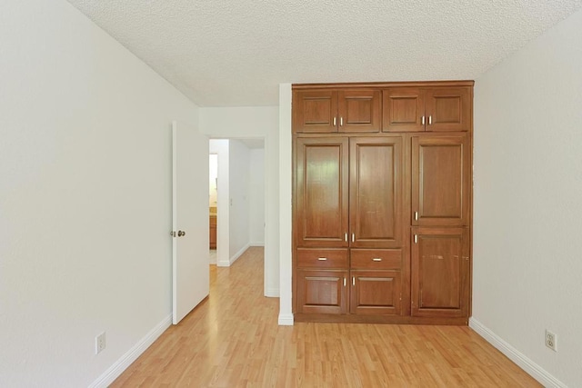 unfurnished bedroom with a textured ceiling and light wood-type flooring