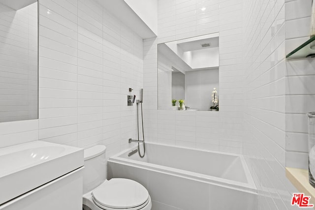 full bathroom featuring vanity, toilet, tiled shower / bath combo, and tile walls