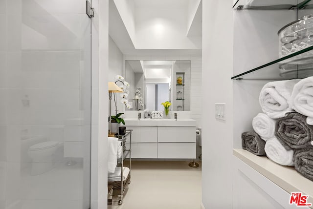 bathroom with vanity, a shower with door, and toilet