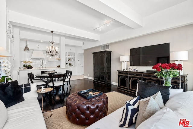 living room with dark hardwood / wood-style floors, a notable chandelier, and beam ceiling