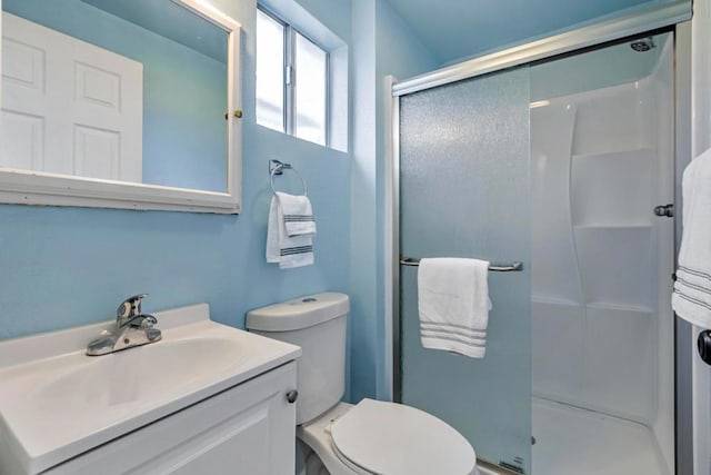 bathroom featuring vanity, a shower with shower door, and toilet