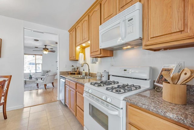 kitchen with sink, light tile patterned floors, ceiling fan, light stone countertops, and white appliances