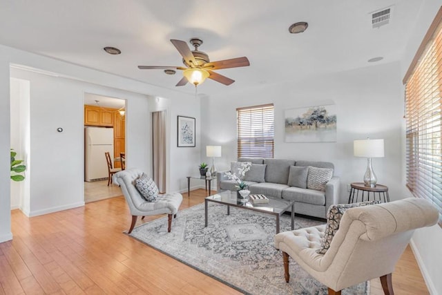 living room with light hardwood / wood-style flooring and ceiling fan