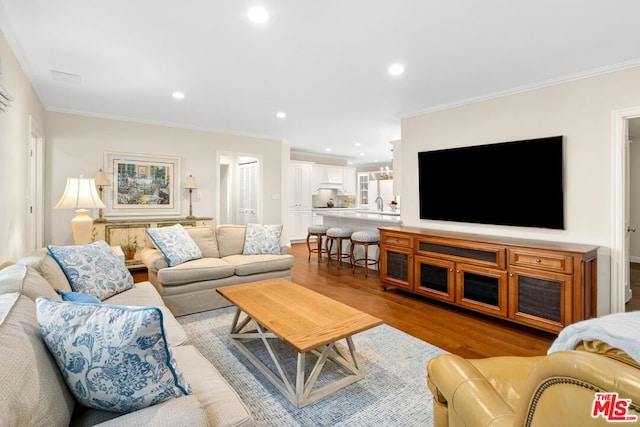 living room featuring crown molding, sink, and light hardwood / wood-style floors