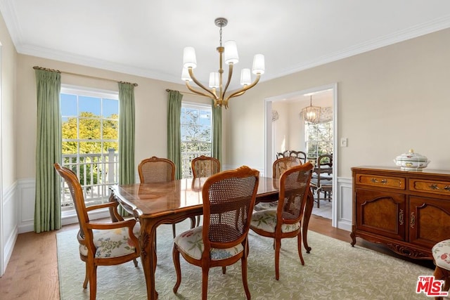 dining space with an inviting chandelier, ornamental molding, and light wood-type flooring