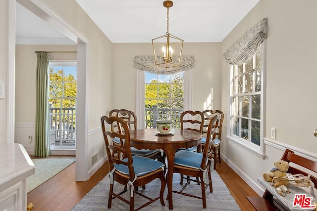 dining room with crown molding, dark hardwood / wood-style floors, a chandelier, and a wealth of natural light