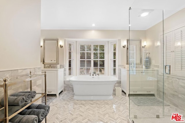 bathroom featuring independent shower and bath, vanity, ornamental molding, and tile walls