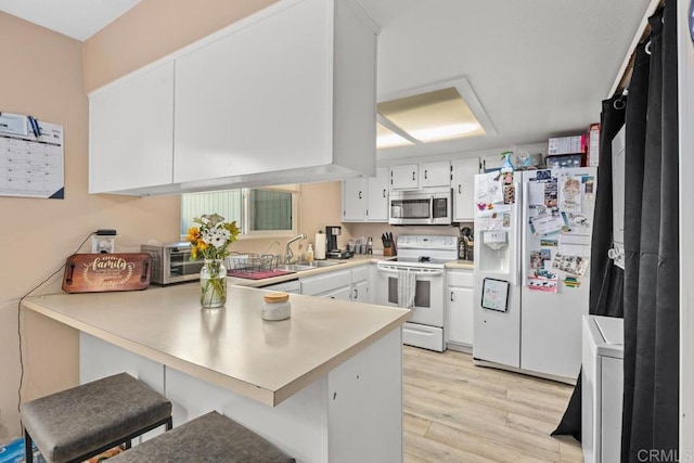 kitchen with white cabinetry, sink, a kitchen breakfast bar, kitchen peninsula, and white appliances