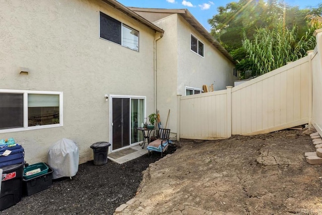 back of property featuring fence and stucco siding