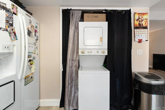 laundry area featuring laundry area, baseboards, stacked washer and dryer, and light wood finished floors