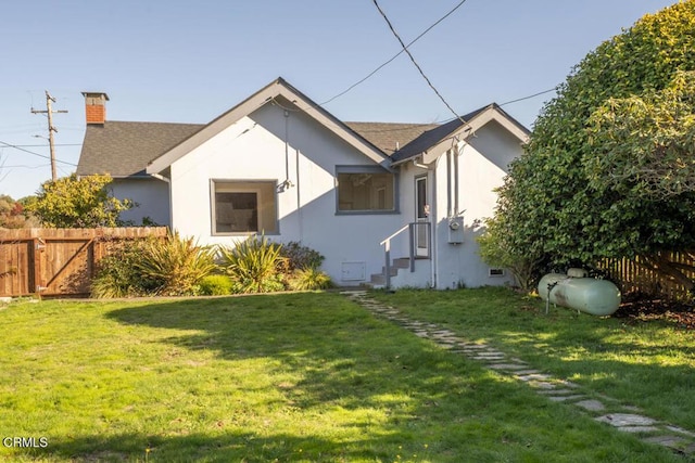 view of front of home with a shingled roof, a chimney, fence, a front yard, and stucco siding