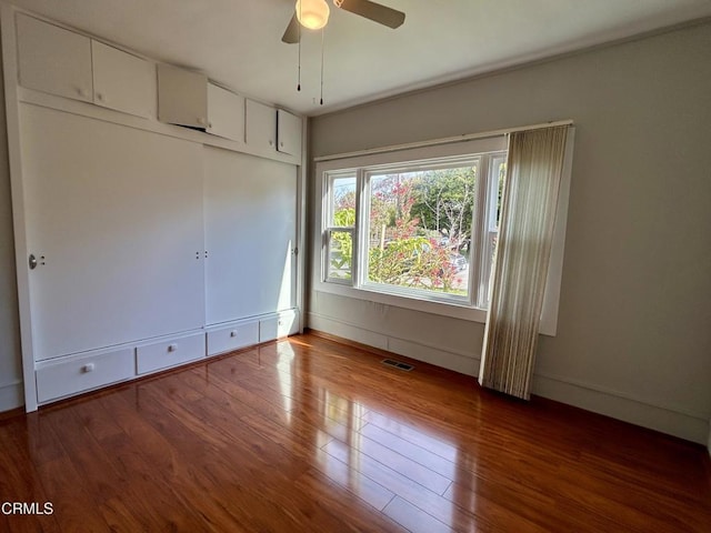 unfurnished bedroom with a closet, wood-type flooring, visible vents, and baseboards