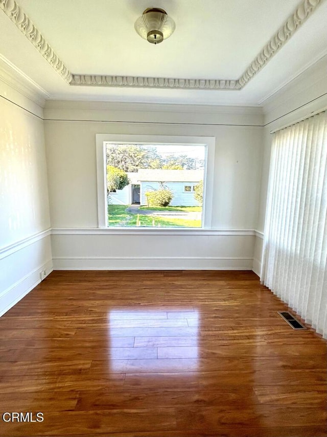 unfurnished room with wood finished floors, visible vents, and baseboards