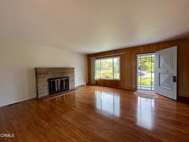 unfurnished living room featuring a fireplace, wood finished floors, and visible vents