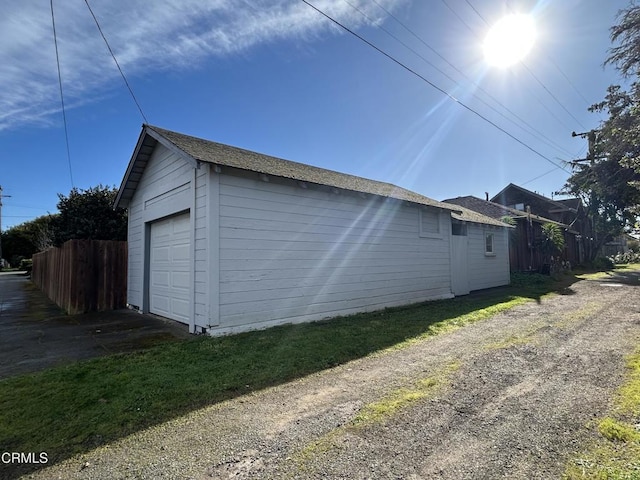 view of home's exterior with fence and an outbuilding