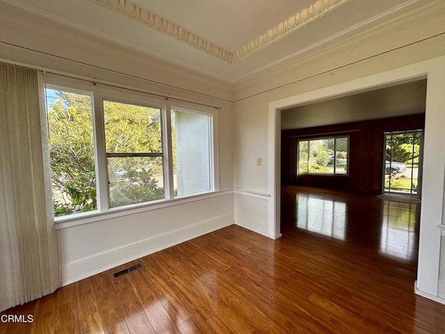 spare room with a healthy amount of sunlight, baseboards, visible vents, and wood finished floors