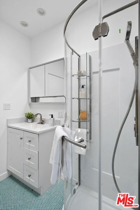 bathroom with vanity, a shower with shower door, and tile patterned flooring