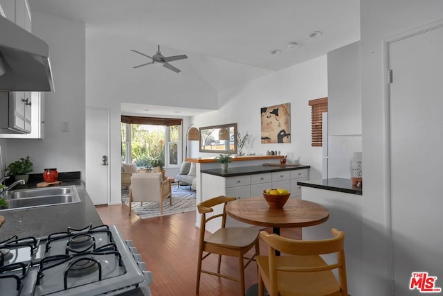 dining space with ceiling fan, wood-type flooring, high vaulted ceiling, and sink