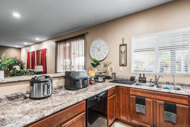 kitchen featuring dishwasher, light stone countertops, and sink