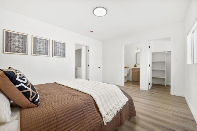 bedroom featuring ensuite bath, light wood-type flooring, a closet, and a walk in closet