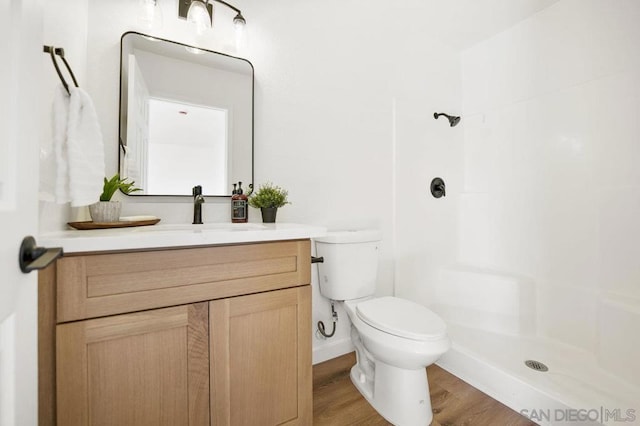 bathroom with hardwood / wood-style flooring, vanity, toilet, and a shower