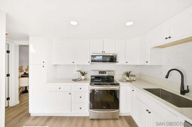 kitchen featuring white cabinetry, stainless steel appliances, sink, and decorative backsplash