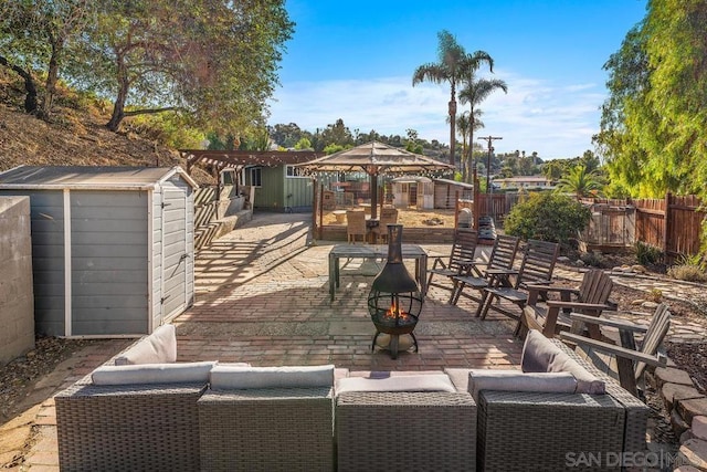 view of patio / terrace with a gazebo, an outdoor living space with a fire pit, and a storage unit